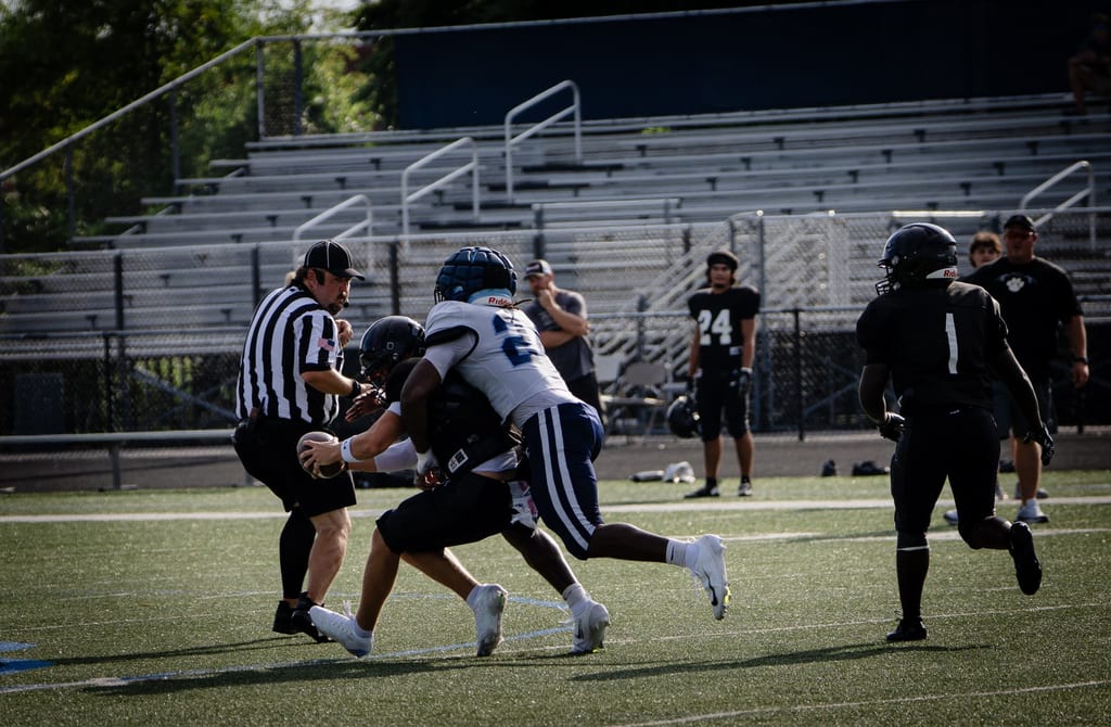 Defender driving through a ball carrier in daylight